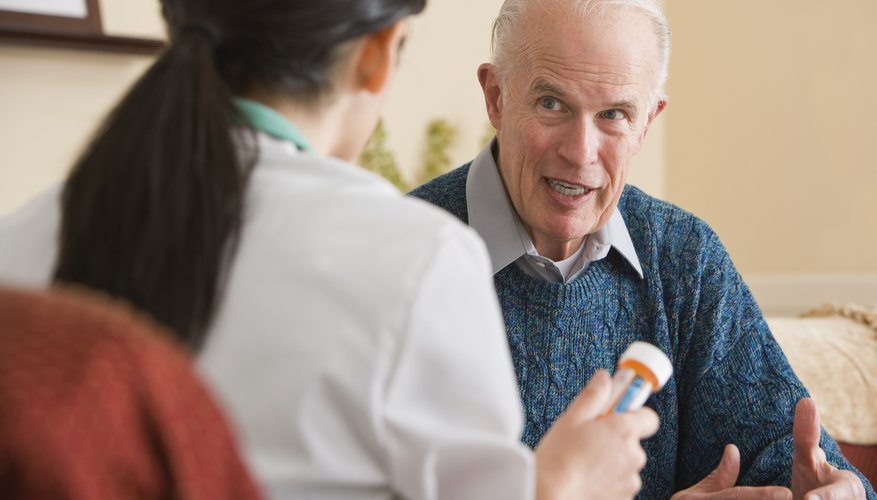 An elderly male patient talks to a nurse about medication