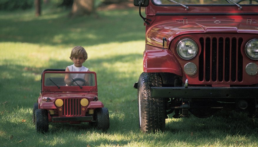 Child driving toy car next to real car