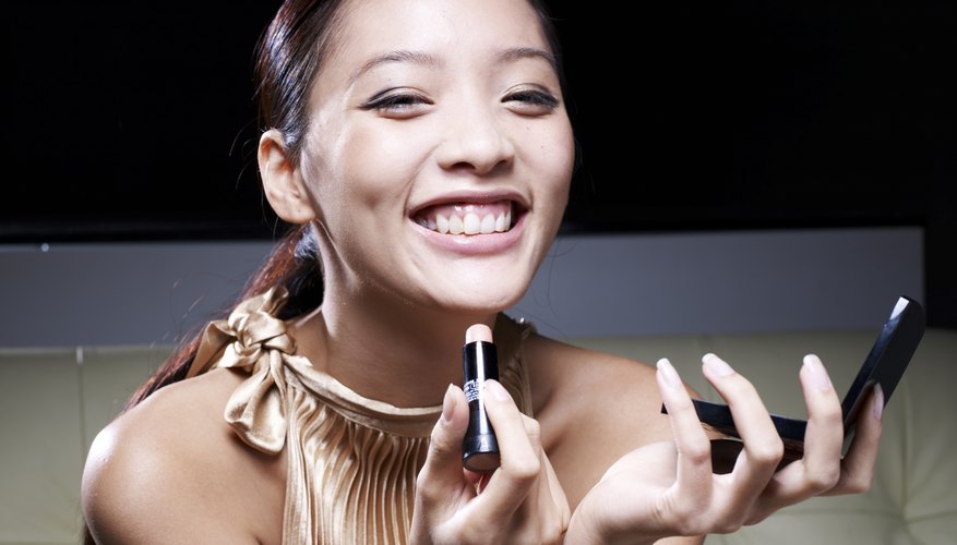 Photo Credit: TAGSTOCK1/iStock/Getty Images A woman applying lipstick.