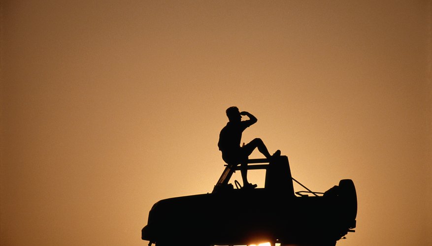 Man sitting on top of off road vehicle, silhouette