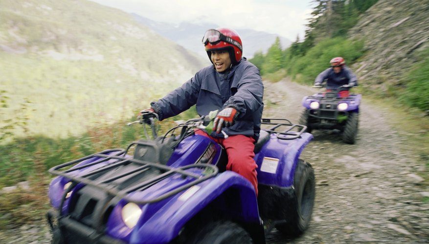 Couple riding ATV's on dirt road in mountains, blurred motion