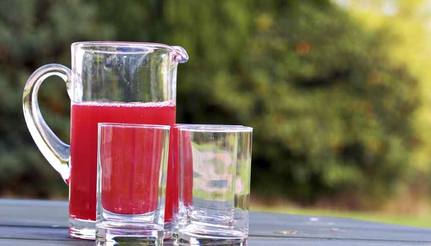 Pitcher of cranberry juice and drinking glasses on a wooden table Pitcher of cranberry juice and drinking glasses on a wooden table
