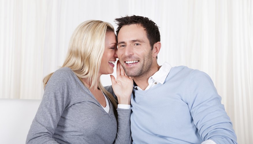Young wife whispering to her husband Young wife whispering to her husband