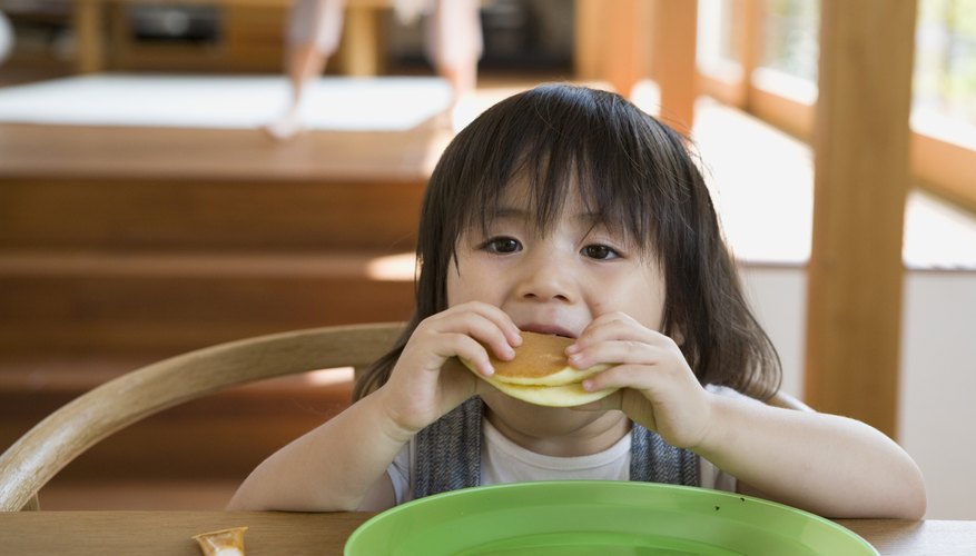A toddler eats her pancakes. A toddler eats her pancakes.