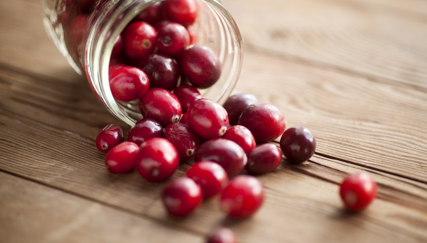 Cranberries spilling out of a jar onto a wooden table Cranberries spilling out of a jar onto a wooden table
