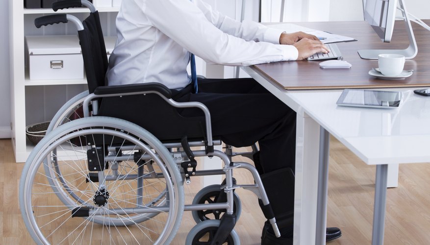 Businessman Sitting On Wheelchair And Using Computer