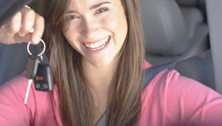 Smiling teenage girl holding keys inside car