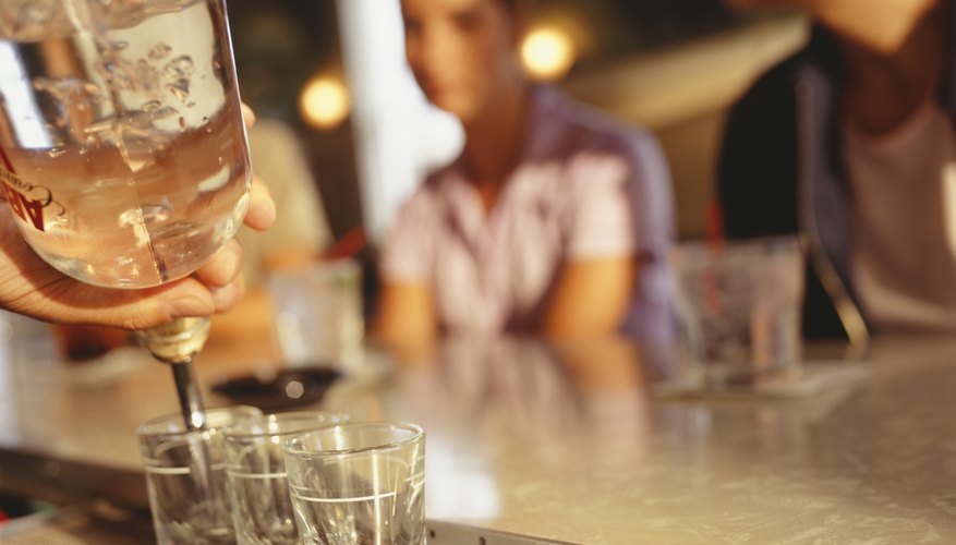 Barman pouring three shorts, close up of drinks