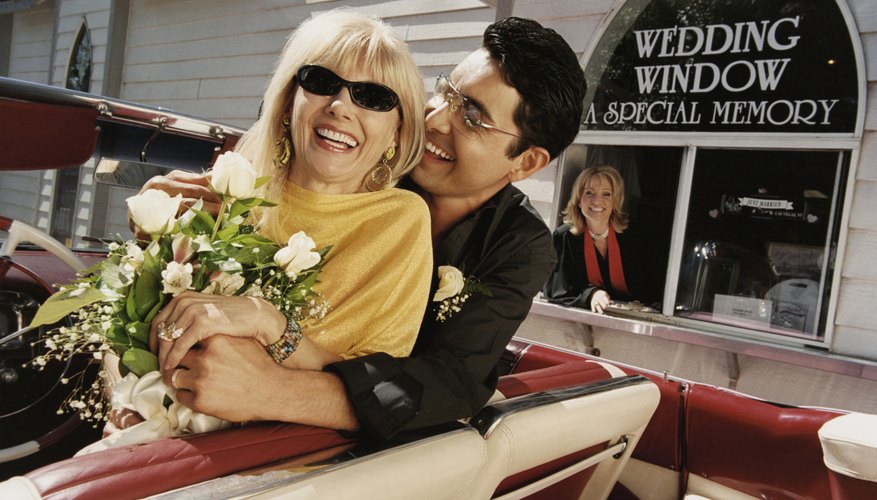 Smiling, Newlywed Couple Sitting in the Front Seat of Their Convertible by a Drive in Church
