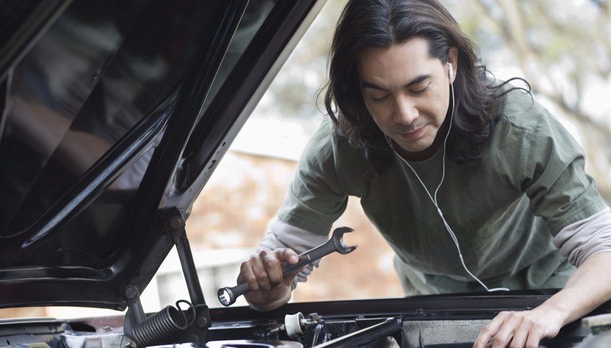 Man working on car and listening to headphones