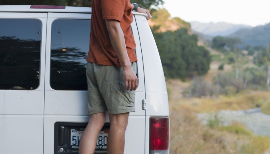 Man standing on the bumper of a van.