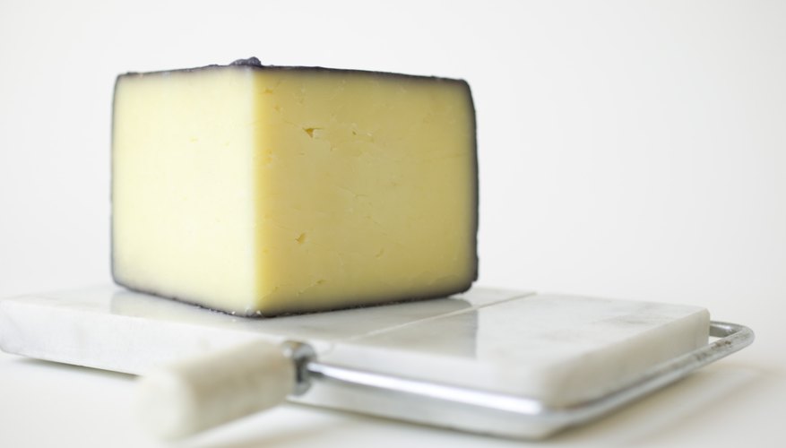 A wedge of cheese on a cutting board. A wedge of cheese on a cutting board.