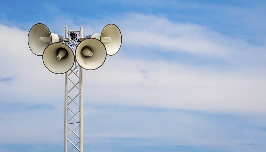A tower with loudspeakers against a summer sky. A tower with loudspeakers against a summer sky.