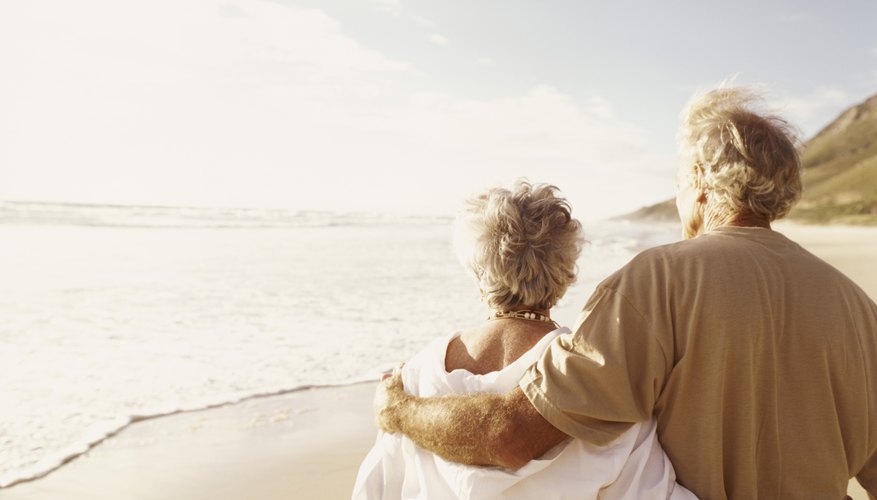 A retired couple walking along the beach.