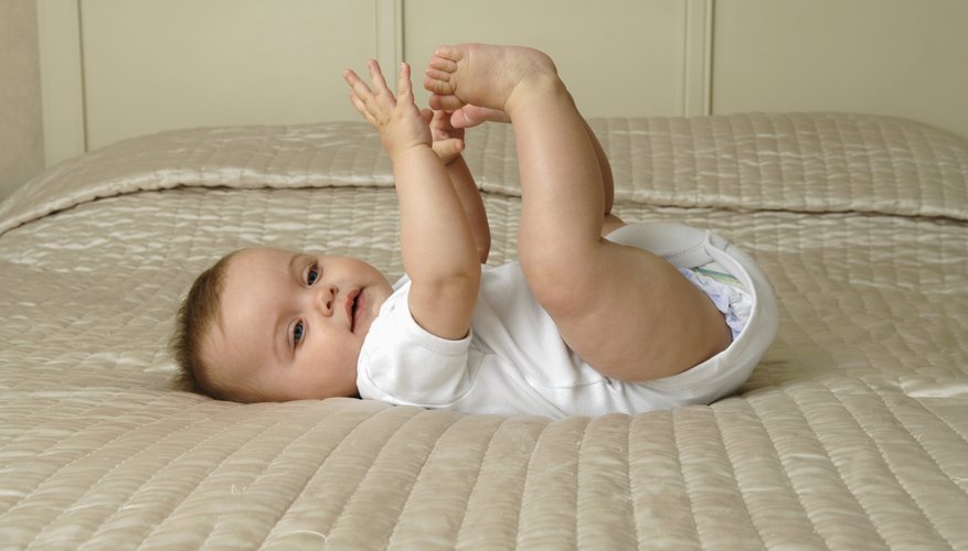 A baby on the bed playing with her feet. A baby on the bed playing with her feet.