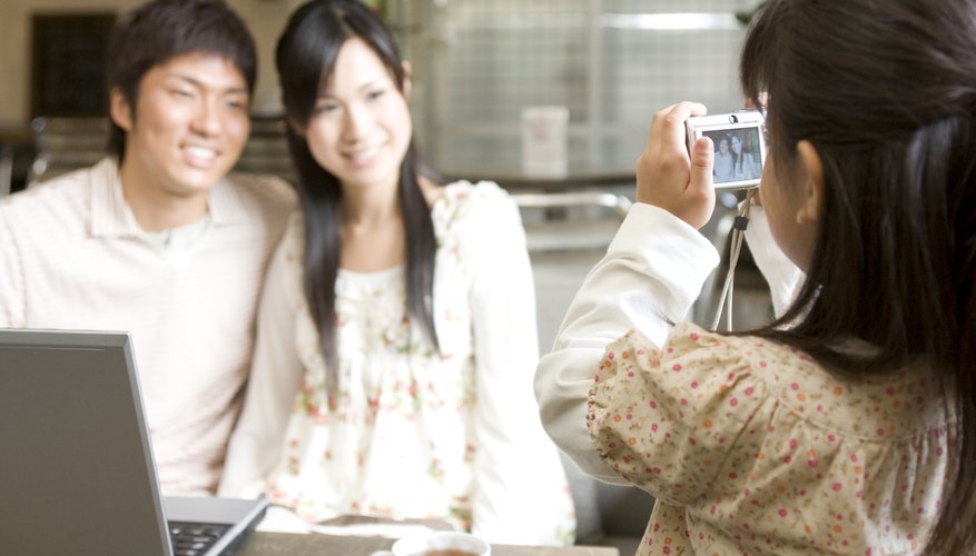 A young girl taking a digital photo of her parents at home. A young girl taking a digital photo of her parents at home.