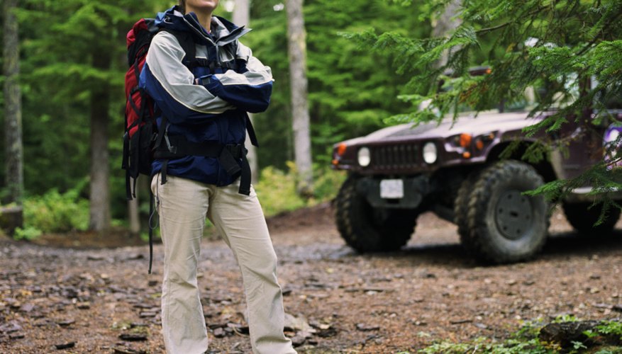 Young woman standing in front of off road vehicle in forest, portrait