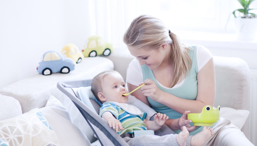 Mother feeding baby while sitting on couch. Mother feeding baby while sitting on couch.