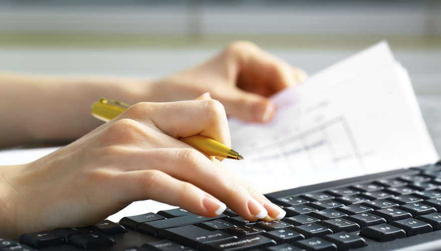 Photo Credit: VikZa/iStock/Getty Images A close-up of a woman doing financial paperwork.