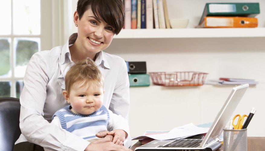 Woman working at home with a baby on her lap. Woman working at home with a baby on her lap.