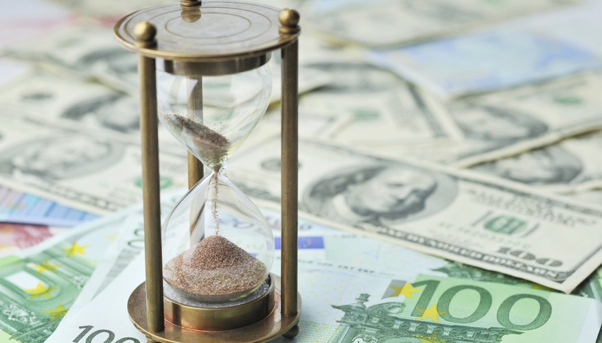 A close-up of an hourglass on bank notes.