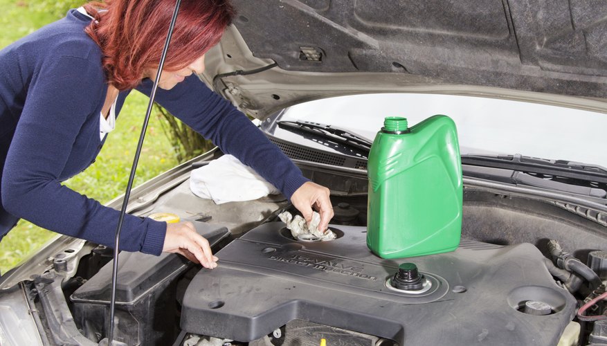 Photo Credit: PeterTG/iStock/Getty Images Woman adding oil to car
