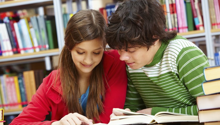 Photo Credit: shironosov/iStock/Getty Images Student tutor helping another student in library.