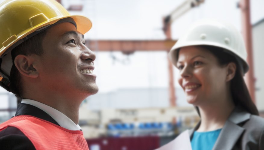 Two engineers smiling in protective workwear outside in a shipping yard