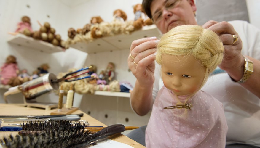 A woman styling a doll's hair in her studio. A woman styling a doll's hair in her studio.