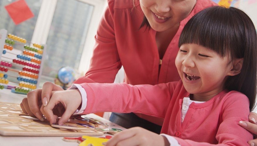 Photo Credit: XiXinXing/iStock/Getty Images Teacher helping a young student with a puzzle.