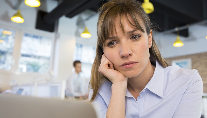 Depressed businesswoman in office behind her laptop