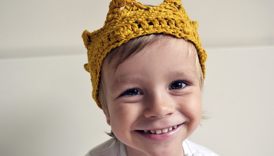 A smiling toddler wearing a knitted crown. A smiling toddler wearing a knitted crown.