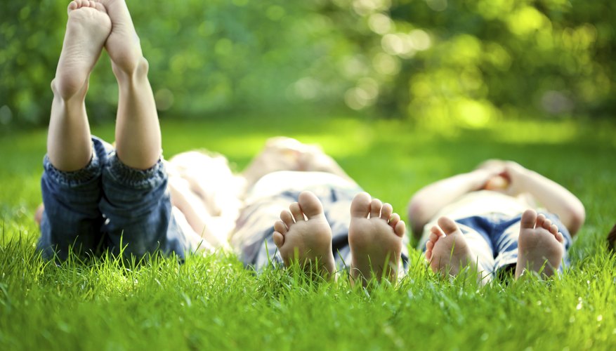Three young children play in the grass together. Three young children play in the grass together.