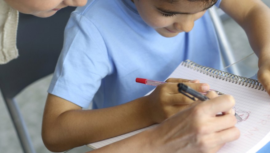 A young woman helps a boy with homework at a day care center A young woman helps a boy with homework at a day care center
