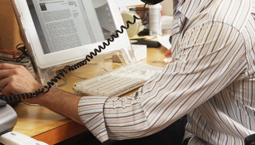 Photo Credit: Christopher Robbins/Digital Vision/Getty Images A man looks at his computer screen while talking on the phone.
