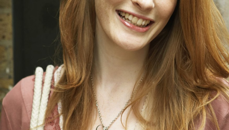 Young woman holding disposable cup, looking away, smiling