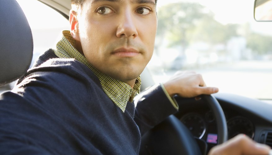 Young man driving, looking over shoulder