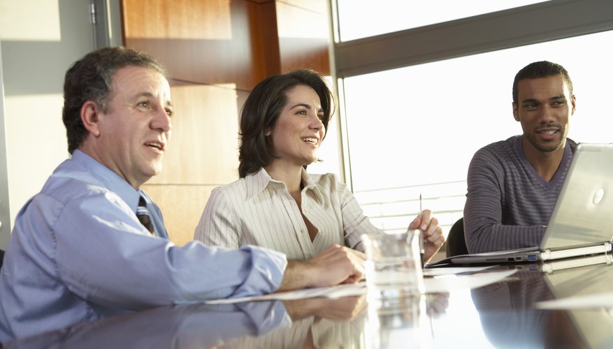 Businessmen and woman at table by laptop in meeting, low angle view
