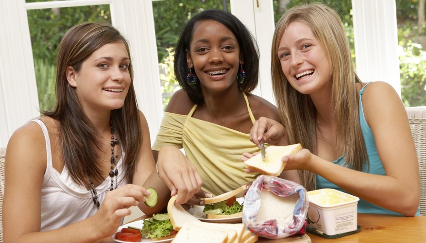 Three girls making sandwiches together. Three girls making sandwiches together.