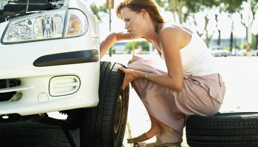 Young woman changing a flat tyre