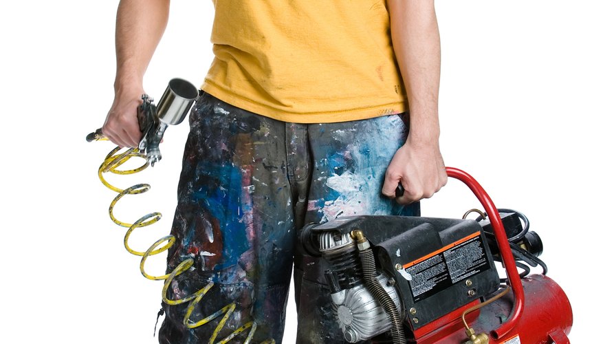 Man holding paint sprayer and air compressor
