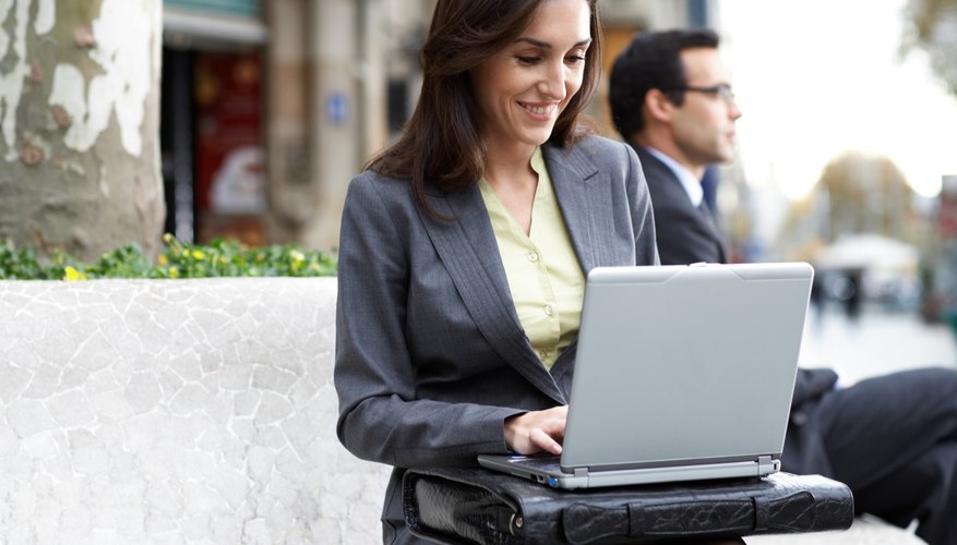 Businesswoman using laptop outdoors, smiling