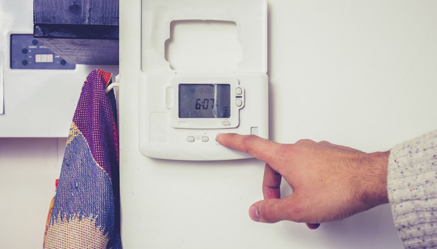 Hand pressing button on central heating controls