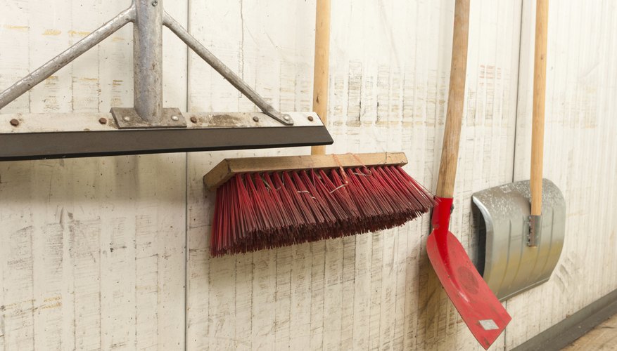 Photo Credit: hans engbers/iStock/Getty Images An assortment of brooms and shovels haning on a wall.