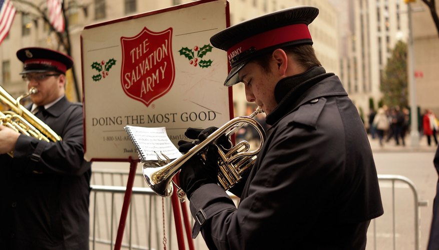 Man playing trumpet in front of The Salvation Army sign.
