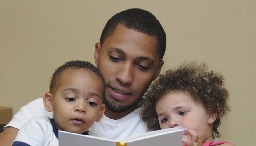 A father reading a book to two toddlers. A father reading a book to two toddlers.