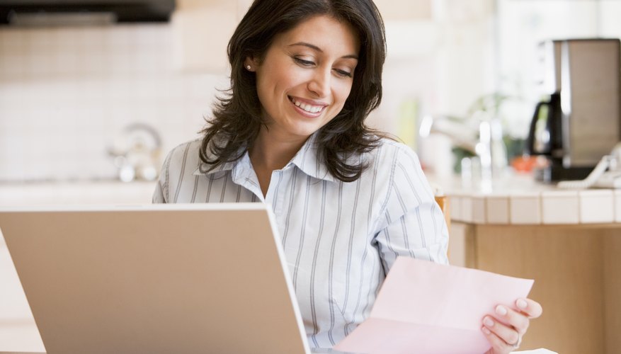 Woman on laptop looking at a paper