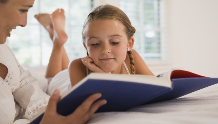 Mother reading with daughter on bed. Mother reading with daughter on bed.
