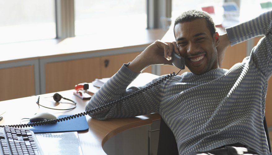 Businessman at desk using telephone, smiling