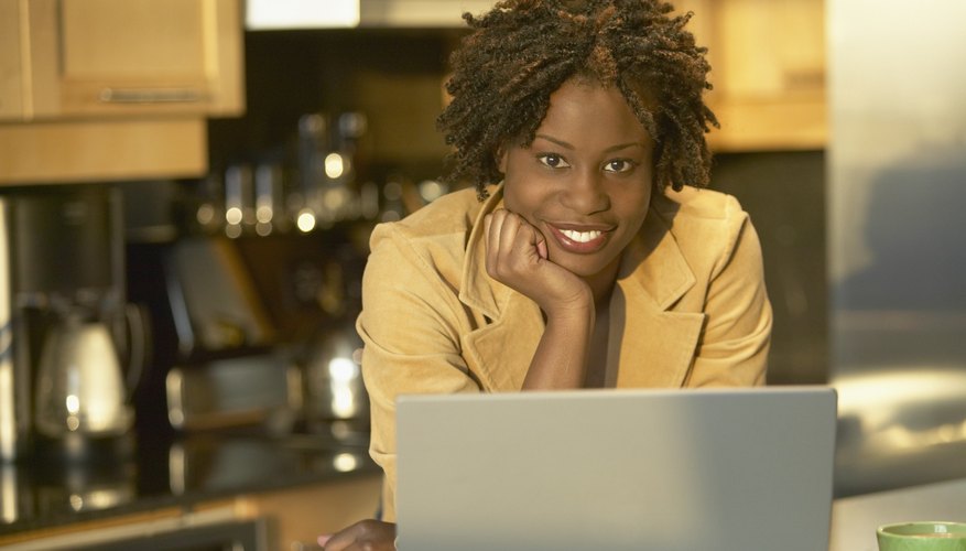 Young African woman in kitchen with laptop